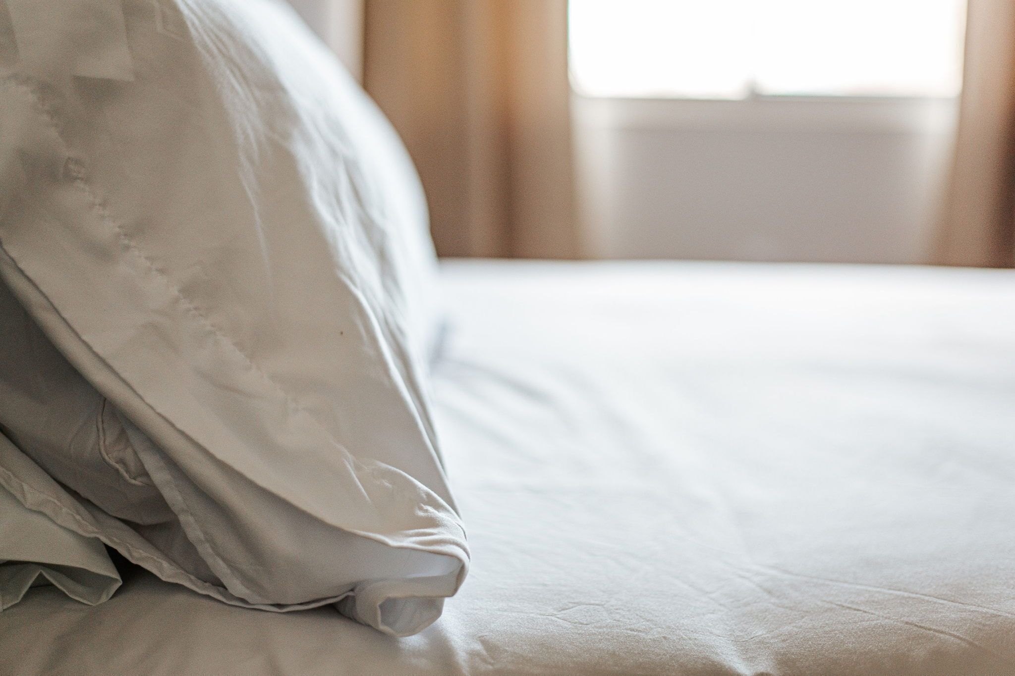 A bed with a white pillow and a neatly made bedspread.