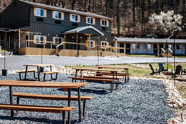 En bygning med mange vinduer og en overdækket indgang, omgivet af grus og træborde.