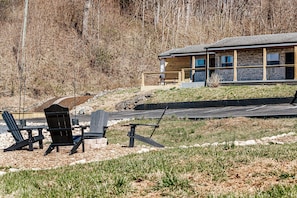 A cabin with a stone exterior, a deck, and outdoor seating.