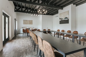 Ein Konferenzraum mit einem langen Tisch, Stühlen, einer Chandelüstere und Kunstwerken an den Wänden.