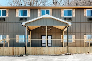 A multi-story building with a covered entrance, wooden shutters, and a simple architectural design.
