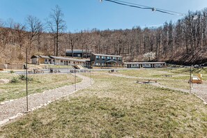 A lodge with a long building, outdoor seating, and a forested backdrop.