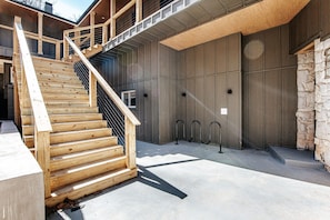 A wooden staircase leading to a second floor, a stone wall, and a metal railing.