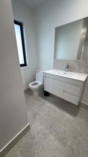 A bathroom with a toilet, sink, and mirror. - 3BR Haven in Stony Rise (Stony Rise)