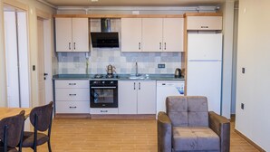 A modern kitchen with white cabinets, a built-in oven, and a coffee maker. - Mimoza Apart (TRABZON)