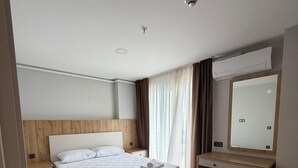 A hotel room with a bed, a desk, a mirror, and a window with curtains. - Mimoza Apart (TRABZON)