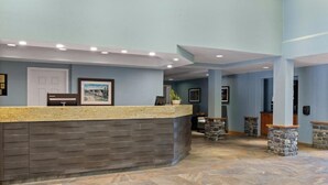 A reception area with a stone counter, framed artwork, and a door. - Serene location, spaceous with pool and easy access to Banff and Lake Louise (Canmore)