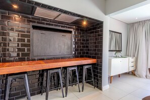 A kitchen with a wooden bar, black tiled backsplash, and a white cabinet.