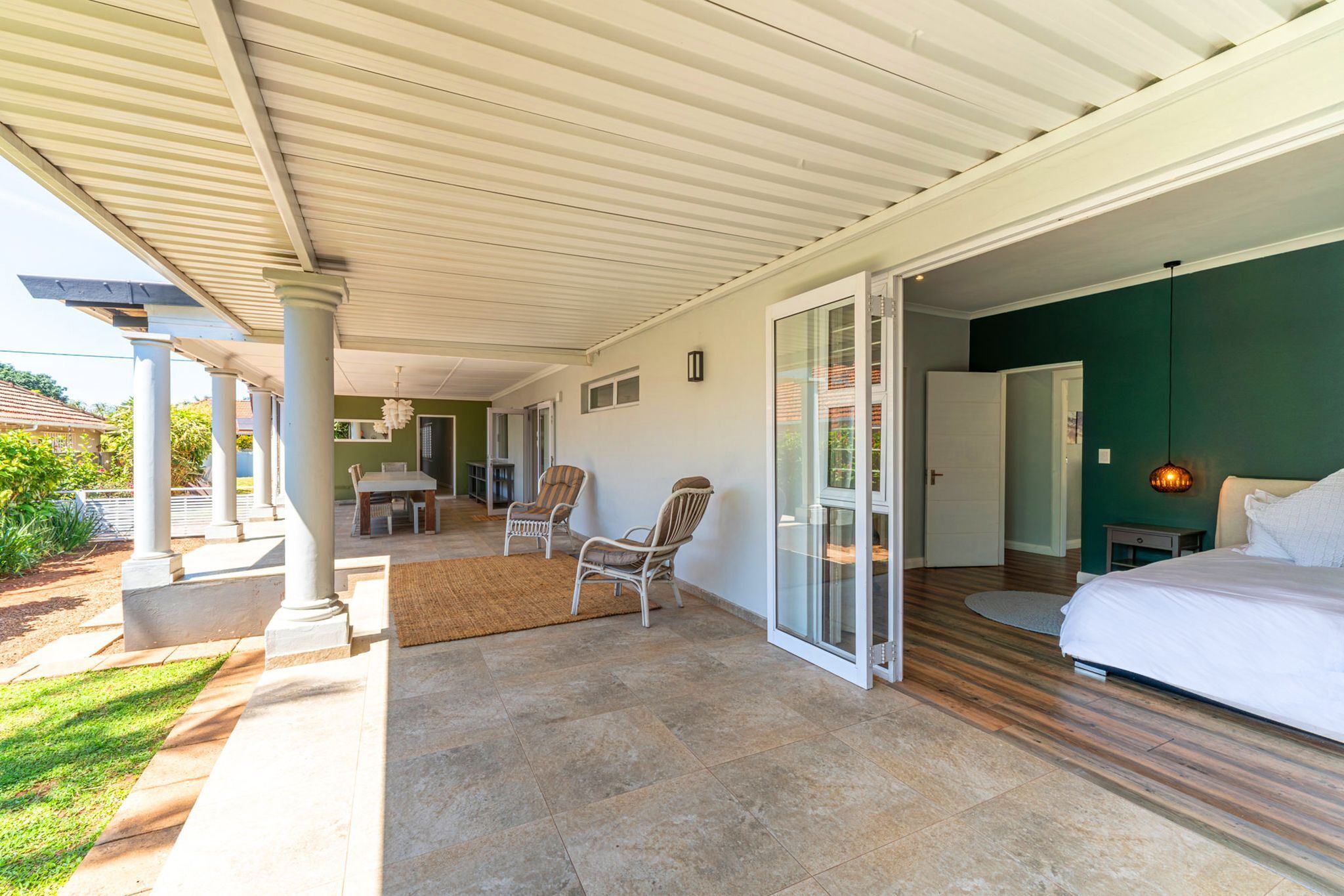 Une chambre avec un grand lit, une porte vitrée donnant sur un balcon et une petite table avec des chaises.
