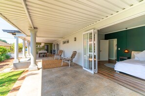 Ein Schlafzimmer mit einem großen Bett, einer Glastür, die auf einen Balkon führt, und einem kleinen Tisch mit Stühlen.