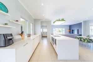 A modern kitchen with white cabinetry, a central island, and a dining area with a table and chairs.