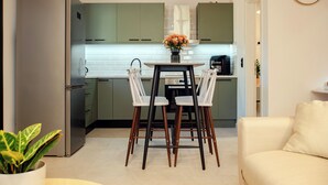 A modern kitchen with green cabinets, a stainless steel refrigerator, a dining table with four chairs, and a potted plant. - 25 meters from the beach (Lefkimmi)