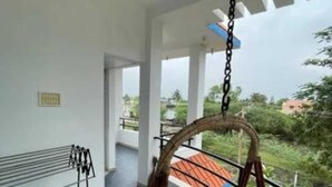 Un balcón con una hamaca colgante, baranda de metal y vistas al verdor.