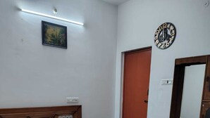 Un dormitorio con cama de madera, una mesita de noche, un espejo, un reloj y un cuadro en la pared.