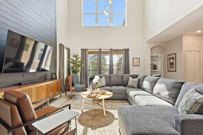 Ein geräumiges Wohnzimmer mit großem Flachbildfernseher, einem Ecksofa, einem Couchtisch und einem Kamin.