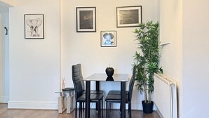 A dining area with a table, chairs, a chandelier, framed pictures, and a potted plant. - 
Cossy two bedroom apartment in Canning Town (London)
