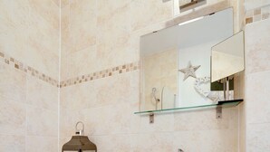 A bathroom with a bathtub, a white vanity with a mirror, and a glass shelf. - 
Cossy two bedroom apartment in Canning Town (London)