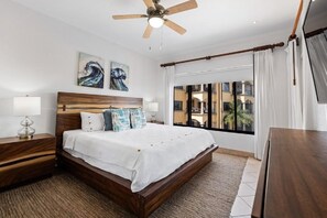 Ein Schlafzimmer mit einem hölzernen Bett, einem Nachttisch mit Lampe, einem Deckenventilator und Bildern an der Wand.