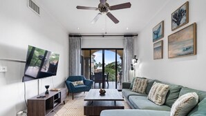 Ein Wohnzimmer mit Fernseher, Sofa, Couchtisch und Deckenventilator.