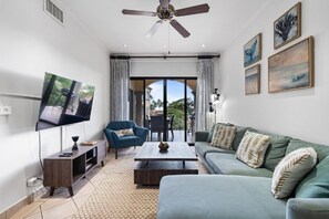 Ein Wohnzimmer mit Fernseher, Sofa, Couchtisch und Deckenventilator.