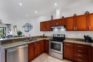 Eine moderne Küche mit Granit Arbeitsplatten, Edelstahlgeräten und Holzschränken, sowie ein Essbereich mit Aussicht.