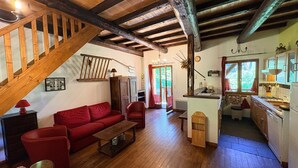 Ein rustikales Interieur mit einer Holztreppe, einem roten Sofa, einem Holztisch und einer Küchenzeile mit Spüle und Herd.