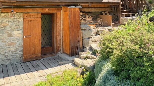 Ein Holzhaus mit Balkon, Steinmauern und einer Holztür.