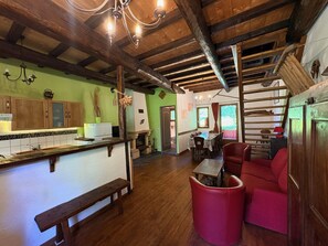 A rustic interior with wooden beams, a kitchen with a bench, and a dining area with red chairs. - Spacious family chalet in a quiet setting with breathtaking views (Albiez-Montrond)