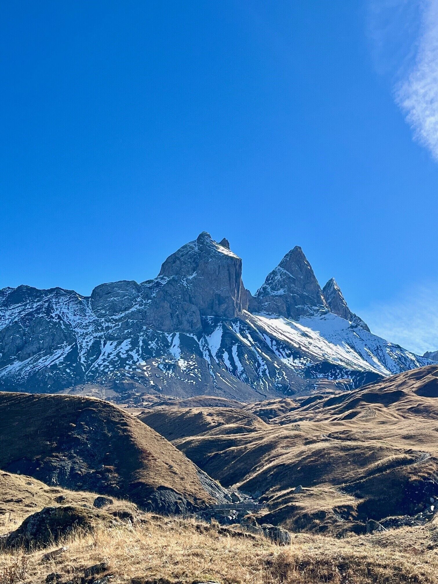 A mountainous landscape with snow-capped peaks and a clear blue sky.