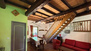Ein Essbereich mit Holztisch und -stühlen, einer Treppe und einem roten Sofa.