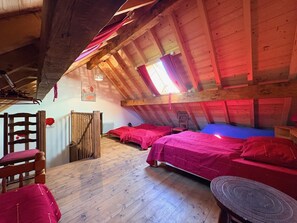Une chambre mansardée au style rustique, avec des poutres en bois, un plafond en pente et un puits de lumière.
