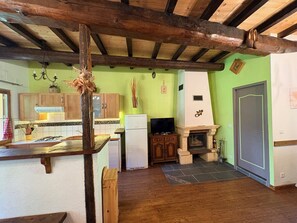 Une cuisine rustique avec des poutres en bois, une cheminée en pierre et un mur végétal.