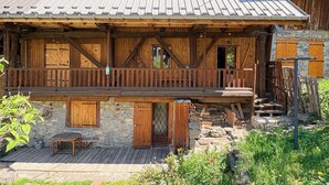 Ein rustikales Holzhaus mit Balkon, Stein Fundament und einem Metall-Dach.