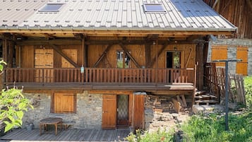 Ein rustikales Holzhaus mit Balkon, Stein Fundament und einem Metall-Dach.