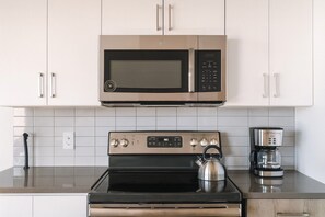 Une cuisine équipée d’un four à micro-ondes en acier inoxydable, d’un four et d’une machine à café.