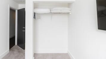 A narrow hallway with a closet containing folded towels and a hanging rack.