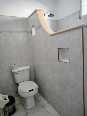 Ein Badezimmer mit Toilette, Dusche und einem kleinen Fenster.
