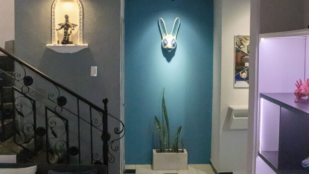 Um interior moderno com uma escada, uma escultura de coelho na parede e um vaso de planta.