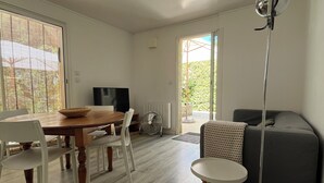 Une pièce comprenant une table à manger, des chaises, un canapé, un lampadaire et un téléviseur.