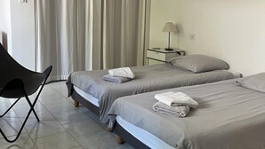 Une chambre avec deux lits, une chaise, une table de chevet et une lampe.