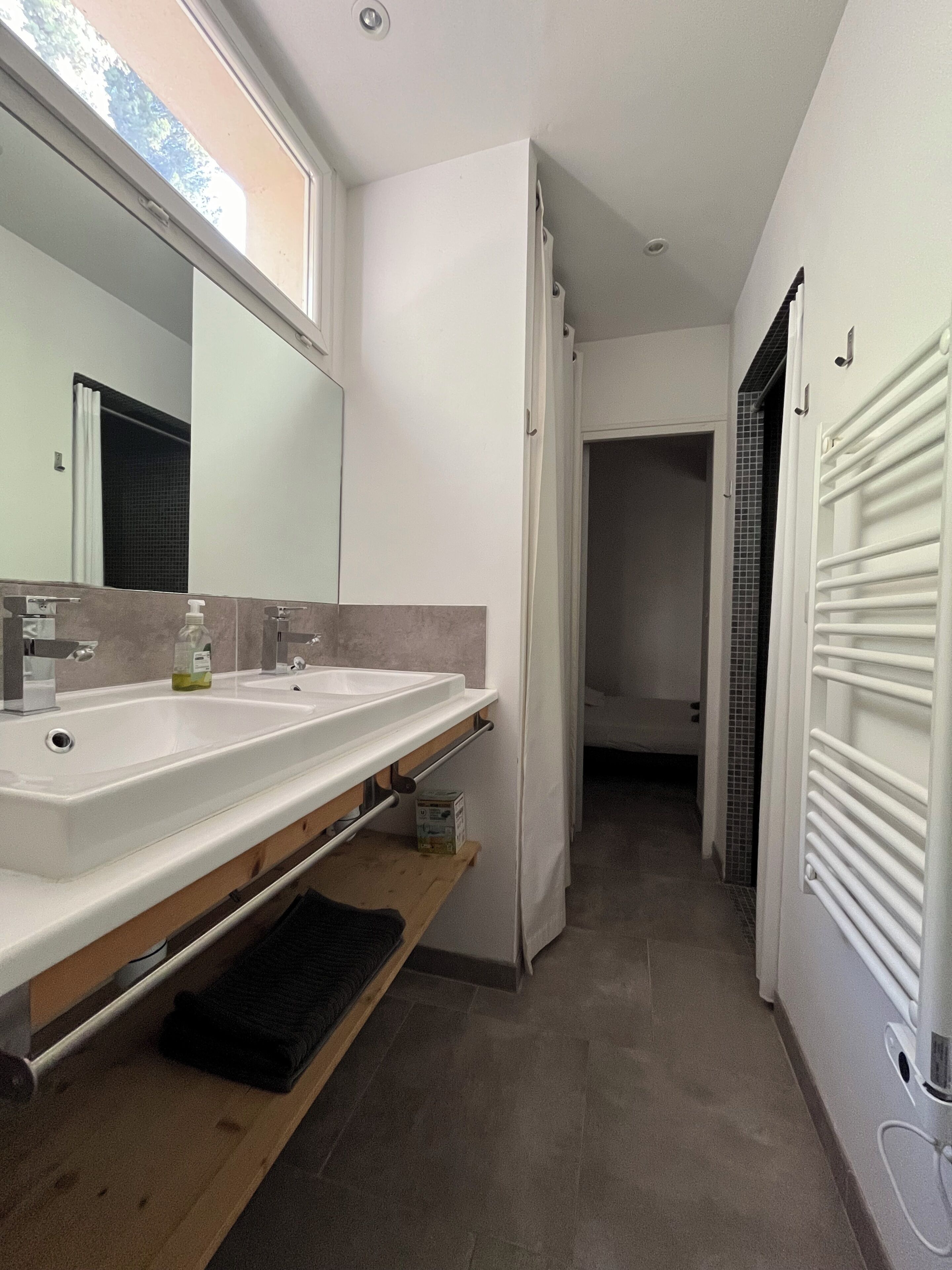 Een moderne badkamer met twee wastafels, een spiegel en een handdoekhouder.