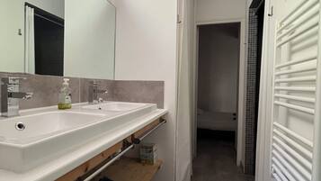 Een moderne badkamer met twee wastafels, een spiegel en een handdoekhouder.