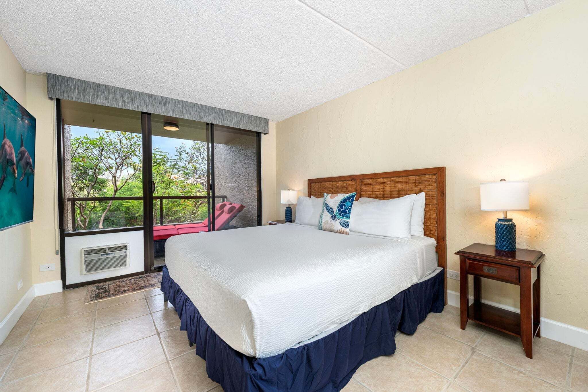 Une chambre d’hôtel avec un grand lit, une table de chevet, une fenêtre donnant sur un beau paysage et un tableau au mur.