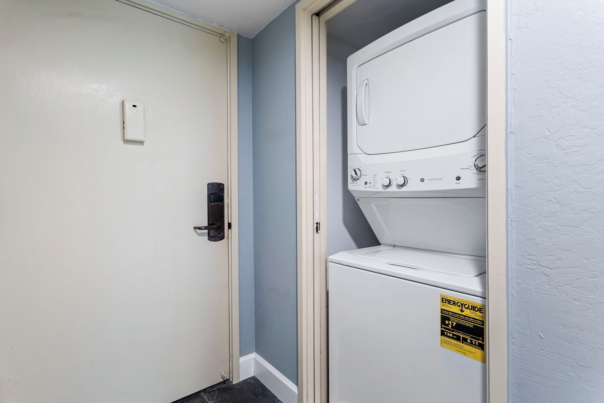 A laundry room with a washer and dryer, a door with a lock, and an ENERGY GUIDE sticker on the dryer.