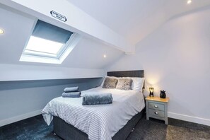 Ein Schlafzimmer mit Oberlicht, einem Bett mit Kissen, einem Nachttisch mit Lampe und einem Schild an der Wand.