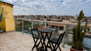 A balcony with a table and chairs, a potted cactus, and a view of a residential area.