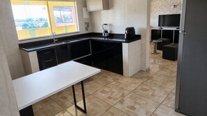 A modern kitchen with a white countertop, black cabinets, a built-in oven, and a refrigerator.