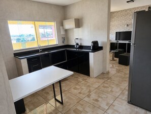 A modern kitchen with a white countertop, black cabinets, a built-in oven, and a refrigerator. - Large house, 2 extra-large bedrooms, office and garage (sleeps up to 4 people and pets) (Contagem)