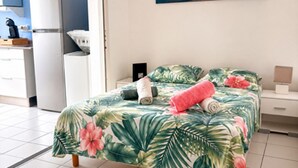 Ein Schlafzimmer mit Bett, einem Gemälde, einer Küchenzeile und einem Badezimmer.