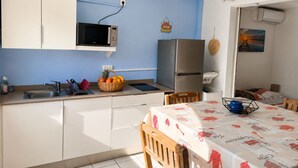 Eine kompakte Küche mit Mikrowelle, Kühlschrank und einem Essbereich mit Tisch und Stühlen.